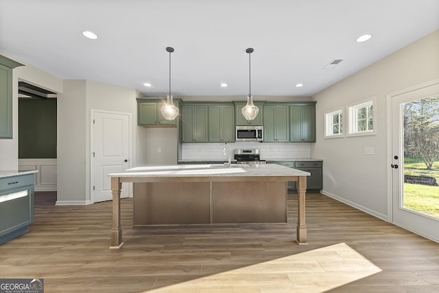 kitchen with decorative light fixtures, light hardwood / wood-style flooring, stainless steel appliances, and green cabinetry