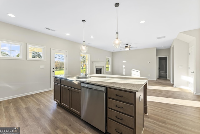 kitchen with dishwasher, a center island with sink, sink, ceiling fan, and light wood-type flooring