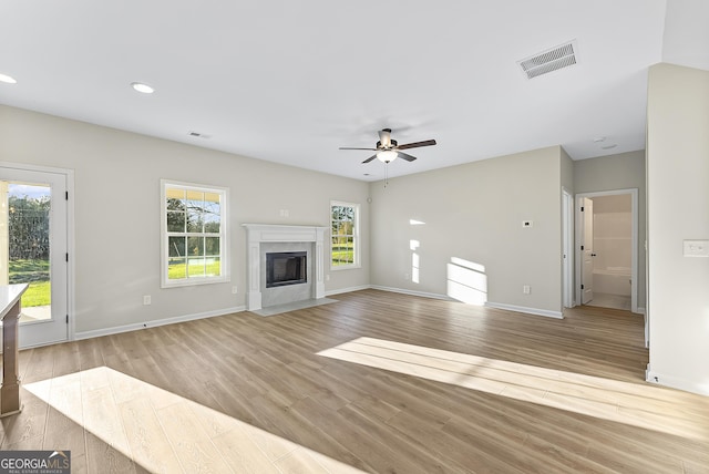 unfurnished living room featuring a premium fireplace, light hardwood / wood-style flooring, and ceiling fan