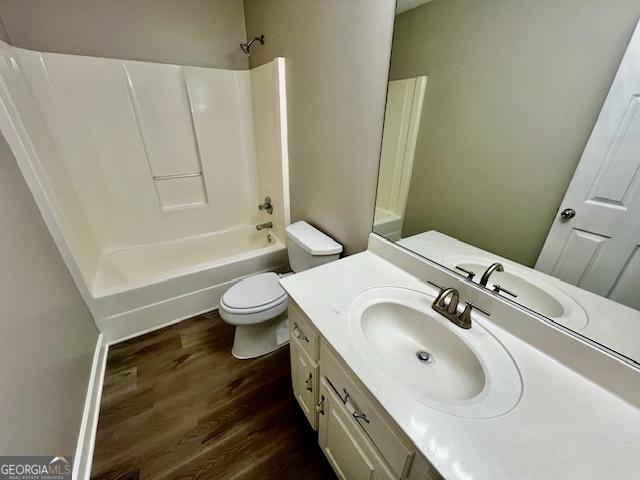 full bathroom with vanity, hardwood / wood-style floors,  shower combination, and toilet