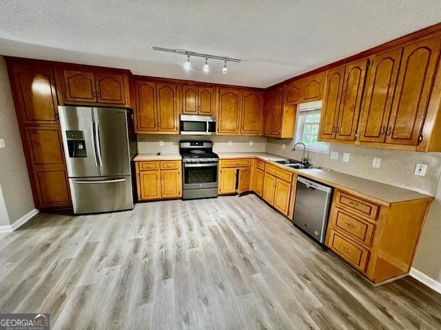 kitchen featuring sink, stainless steel appliances, light hardwood / wood-style floors, and a textured ceiling