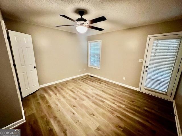 empty room featuring ceiling fan, hardwood / wood-style floors, and a textured ceiling