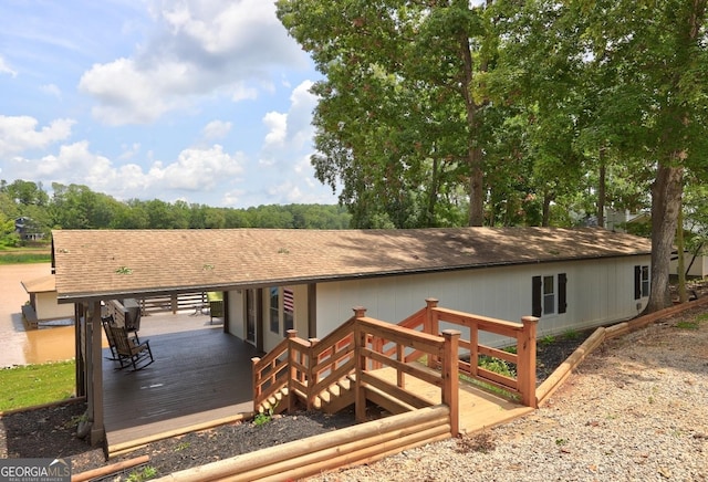 exterior space with a shingled roof and a deck