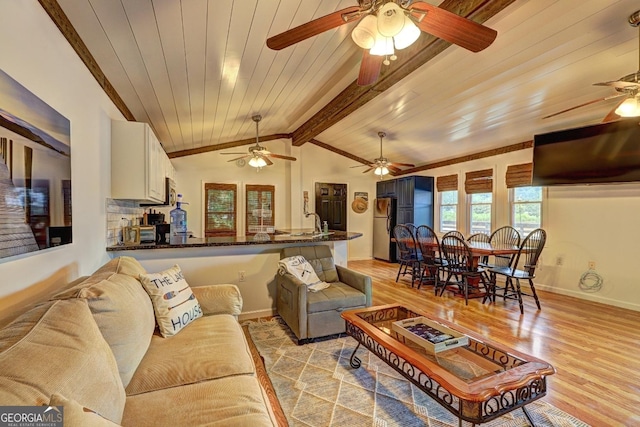 living area featuring vaulted ceiling with beams, light wood-style floors, baseboards, and wooden ceiling