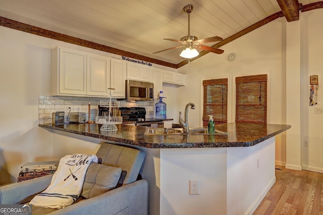 kitchen with vaulted ceiling with beams, light wood finished floors, tasteful backsplash, stainless steel microwave, and electric range