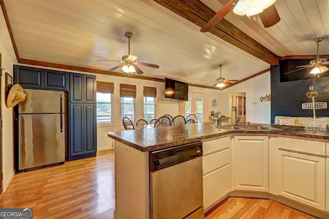 kitchen with lofted ceiling with beams, light wood-style flooring, appliances with stainless steel finishes, and a sink