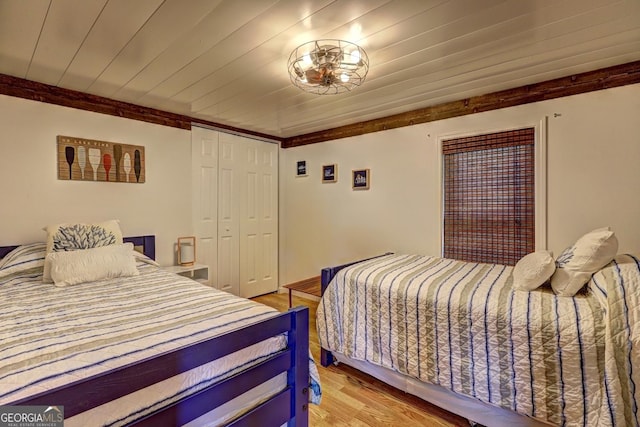 bedroom featuring wooden ceiling, light wood finished floors, ornamental molding, and a closet