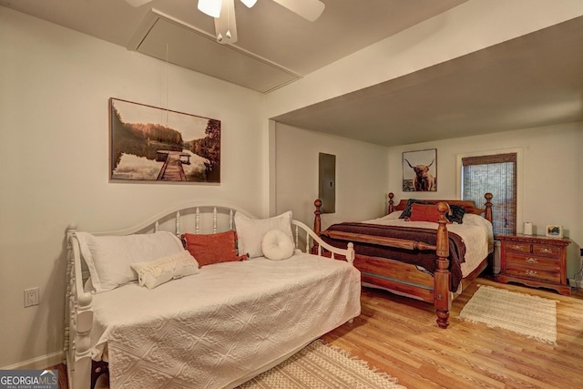 bedroom featuring wood finished floors, attic access, and a ceiling fan