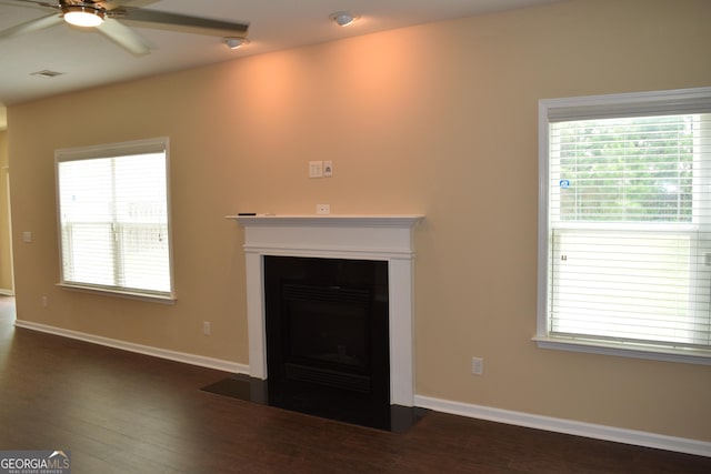 unfurnished living room featuring dark wood-type flooring and ceiling fan