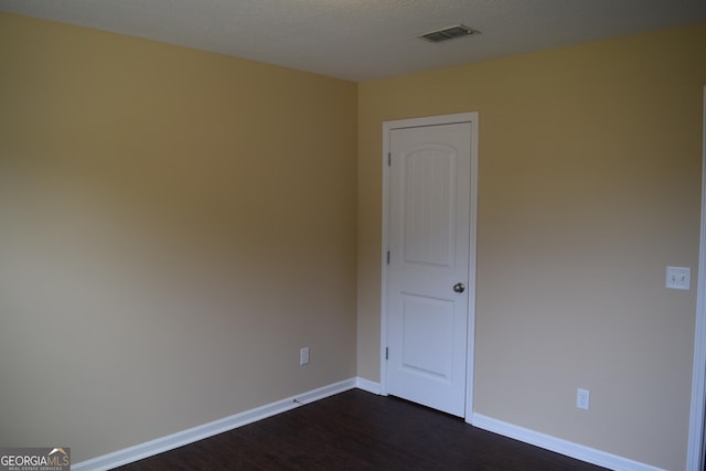 empty room with dark wood-type flooring and a textured ceiling