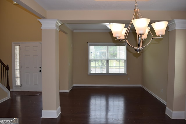 entrance foyer with ornate columns, ornamental molding, a notable chandelier, and dark hardwood / wood-style flooring