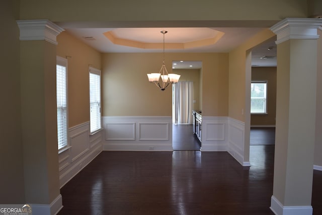 unfurnished dining area with ornate columns, a wealth of natural light, and a tray ceiling