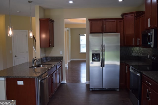 kitchen featuring pendant lighting, sink, dark wood-type flooring, stainless steel appliances, and dark stone counters