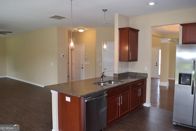 kitchen featuring sink, hanging light fixtures, stainless steel appliances, dark hardwood / wood-style flooring, and dark stone counters