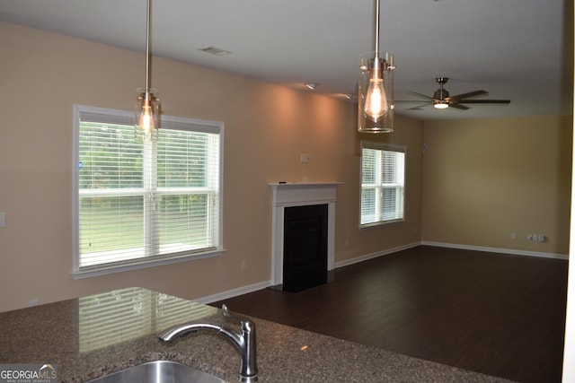 kitchen with dark hardwood / wood-style flooring, decorative light fixtures, ceiling fan, and stone countertops