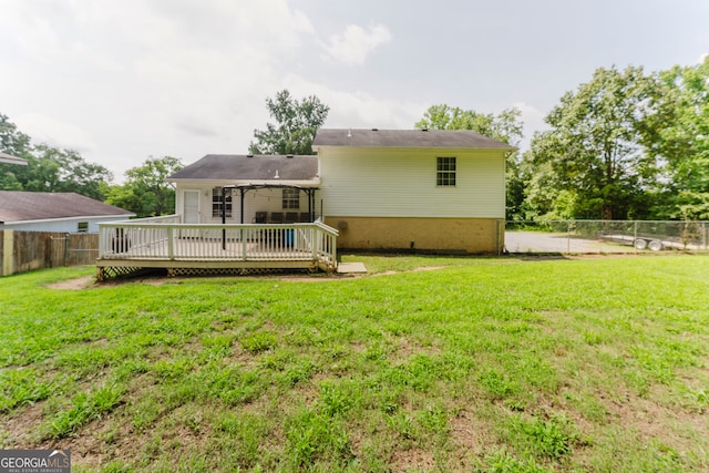 back of property with a deck and a lawn