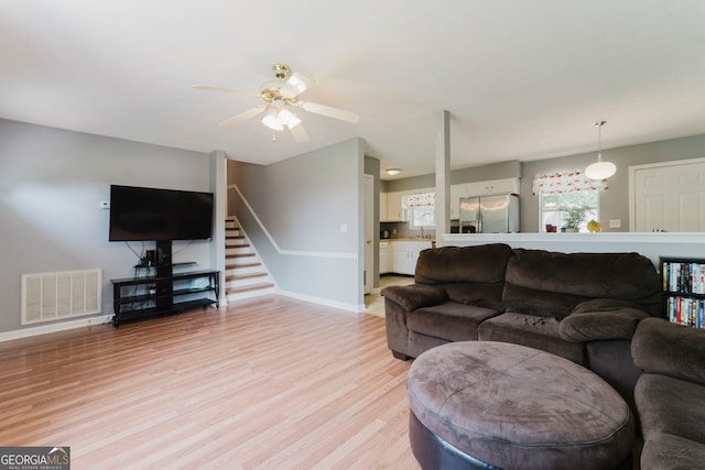 living room featuring ceiling fan and light hardwood / wood-style flooring