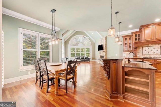 dining space featuring ornamental molding, a stone fireplace, sink, and light wood-type flooring