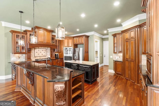 kitchen with sink, hanging light fixtures, a center island with sink, dark stone counters, and stainless steel appliances