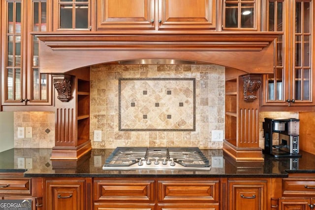 bar with stainless steel gas stovetop, tasteful backsplash, and dark stone counters