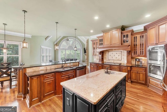 kitchen featuring pendant lighting, an island with sink, sink, dark stone countertops, and stainless steel appliances