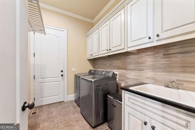 washroom featuring sink, light tile patterned floors, washing machine and dryer, cabinets, and ornamental molding