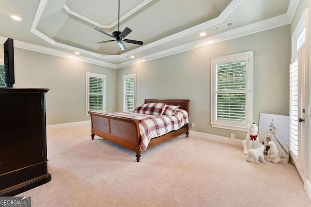 bedroom with light colored carpet, a raised ceiling, and multiple windows