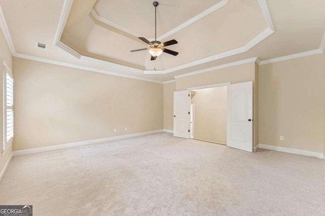 carpeted spare room featuring ceiling fan, ornamental molding, and a tray ceiling