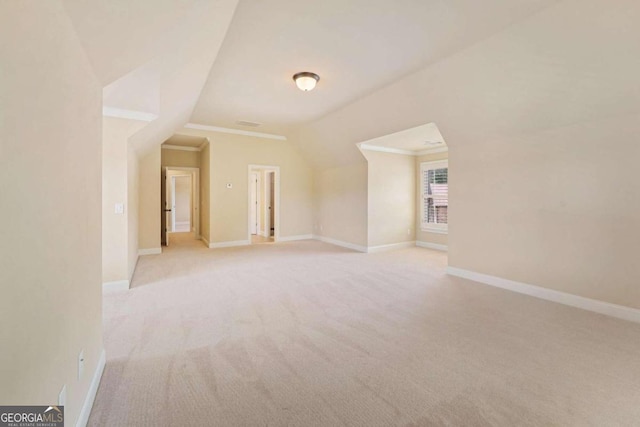 bonus room with vaulted ceiling and light colored carpet