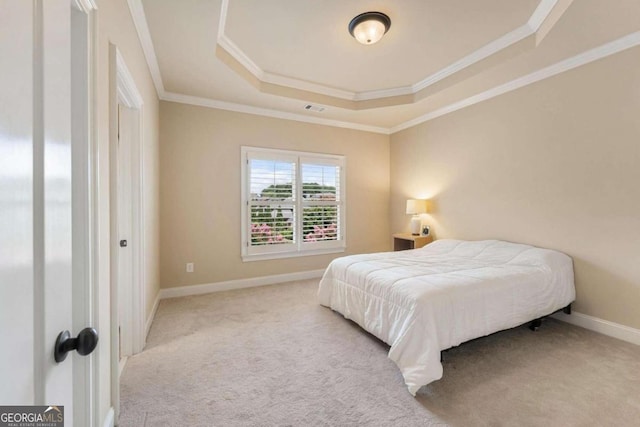 carpeted bedroom featuring ornamental molding and a tray ceiling