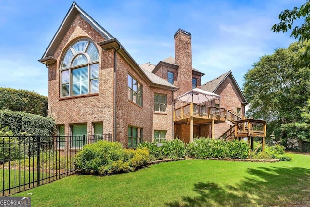 back of property with a wooden deck and a yard