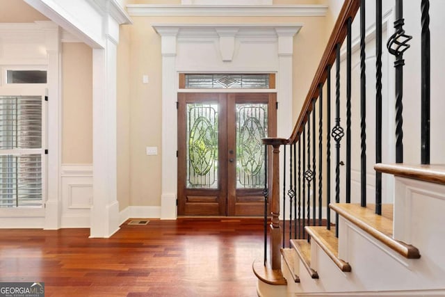 foyer entrance with dark hardwood / wood-style flooring, ornamental molding, and french doors