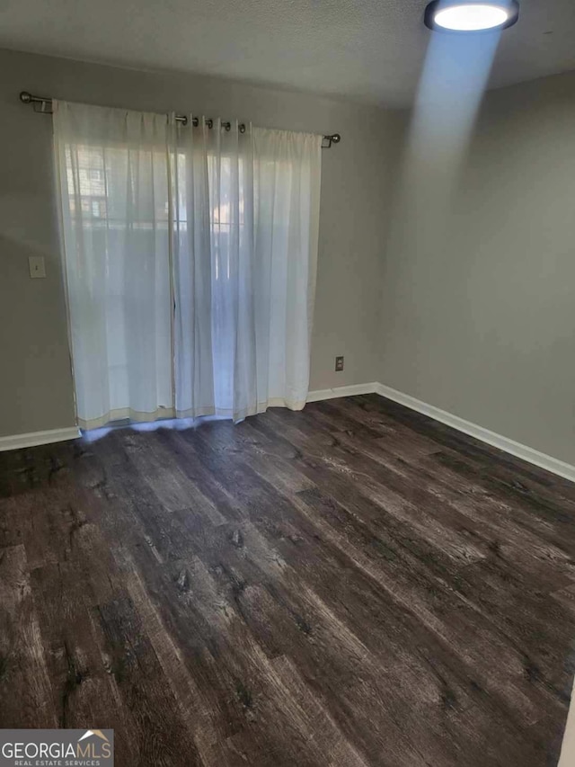 empty room with dark hardwood / wood-style flooring