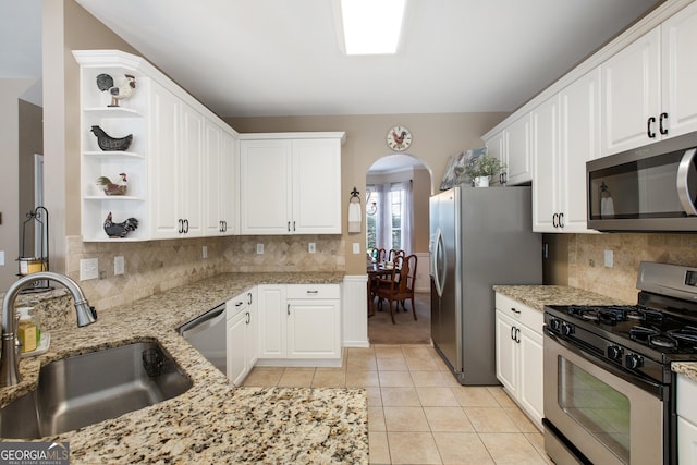 kitchen featuring light tile patterned flooring, sink, light stone counters, stainless steel appliances, and white cabinets