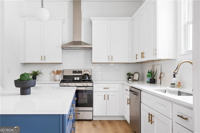 589 Federal Ter SE, Atlanta, GA 30315 - kitchen featuring blue cabinetry, wall chimney range hood, light countertops, appliances with stainless steel finishes, and a sink