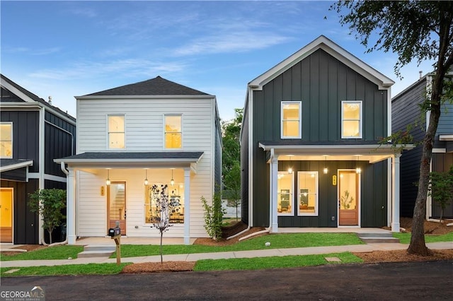 traditional-style home with a porch, roof with shingles, and board and batten siding