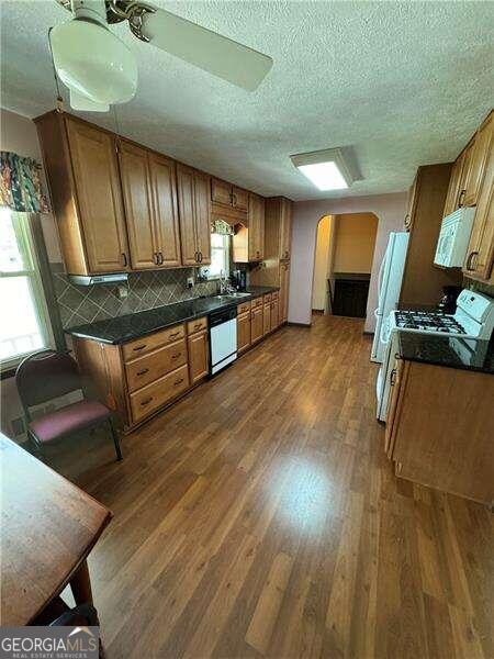 kitchen with tasteful backsplash, white appliances, dark hardwood / wood-style flooring, a textured ceiling, and ceiling fan