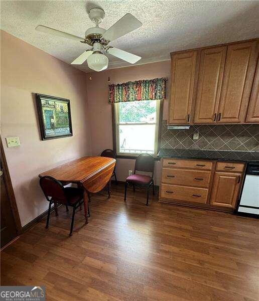 kitchen with hardwood / wood-style flooring, white dishwasher, backsplash, a textured ceiling, and ceiling fan