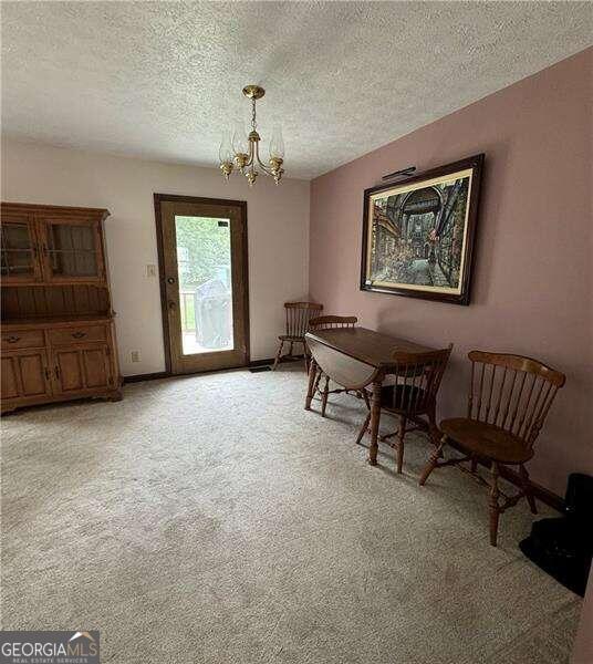 living area with light carpet, a notable chandelier, and a textured ceiling