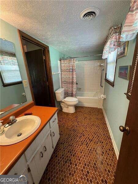 full bathroom featuring vanity, toilet, tile patterned floors, and a textured ceiling