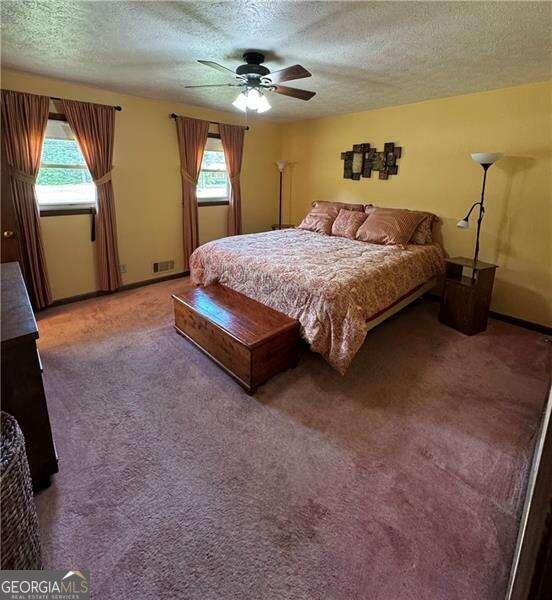 carpeted bedroom with a textured ceiling and ceiling fan