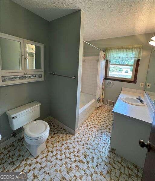 full bathroom featuring vanity, a textured ceiling, tile patterned flooring, and toilet