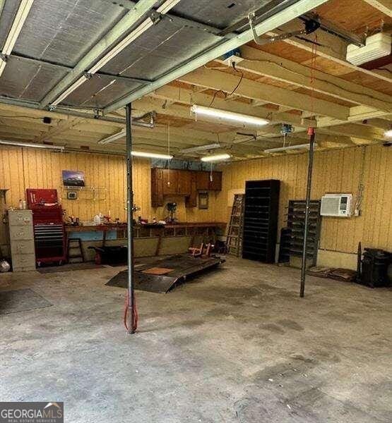 basement with a wall mounted air conditioner, a workshop area, and wooden walls