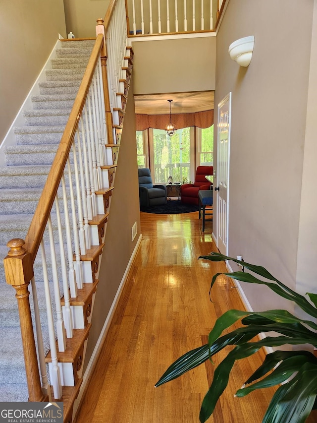 stairs with hardwood / wood-style flooring and a towering ceiling