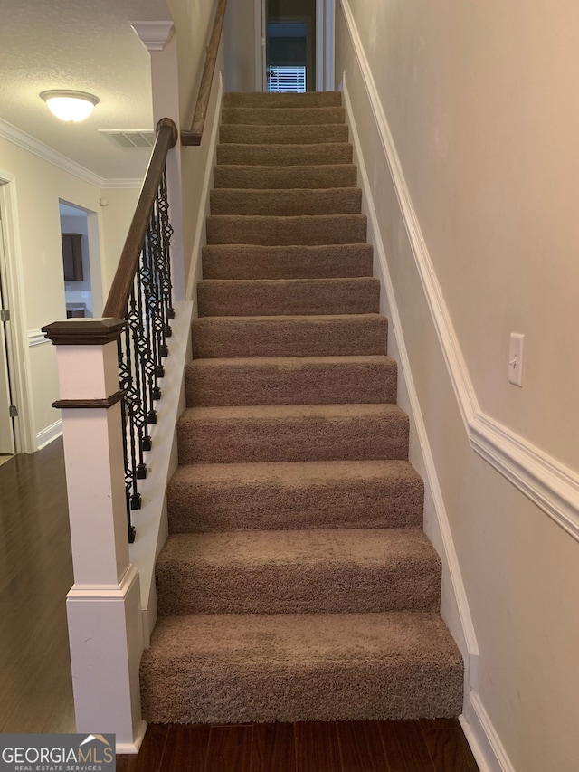 stairway featuring ornamental molding, a textured ceiling, and hardwood / wood-style flooring