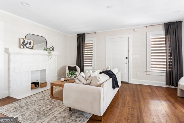 living room featuring dark wood-type flooring, ornamental molding, and a brick fireplace