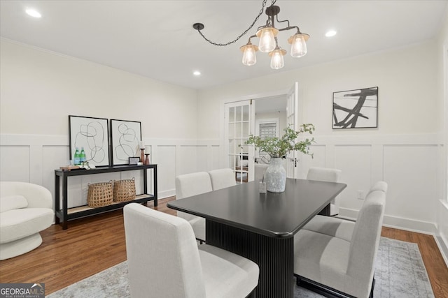 dining space with hardwood / wood-style flooring, ornamental molding, and an inviting chandelier