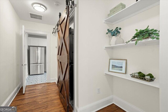 corridor with dark hardwood / wood-style flooring and a barn door