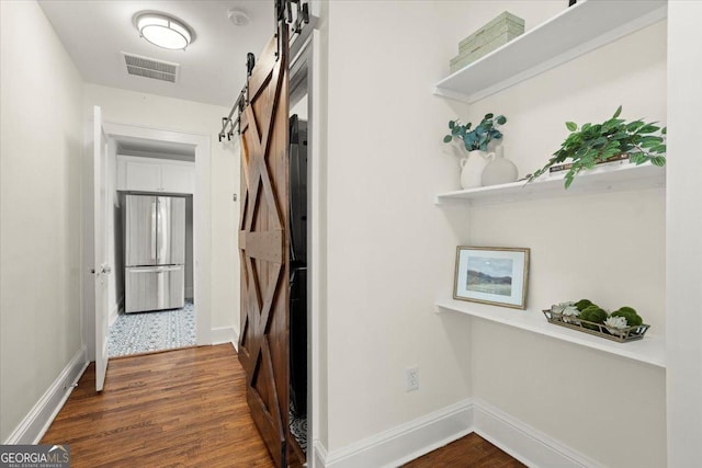 hall with a barn door and dark hardwood / wood-style flooring