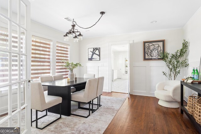 dining room with ornamental molding, an inviting chandelier, and hardwood / wood-style floors